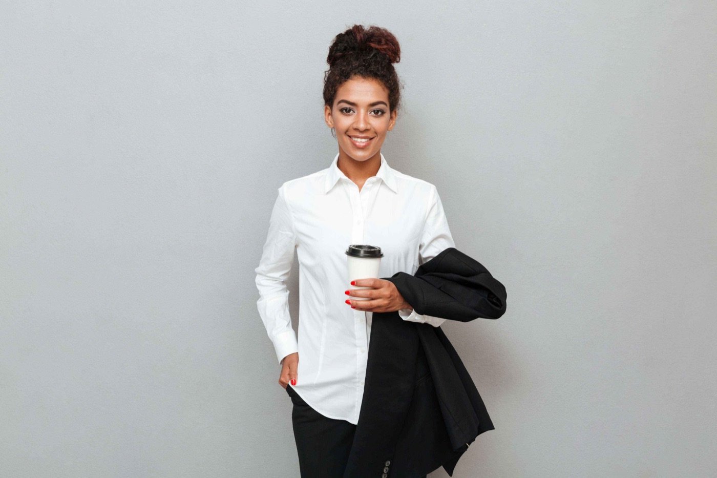 Team member holding a coffee cup and a jacket